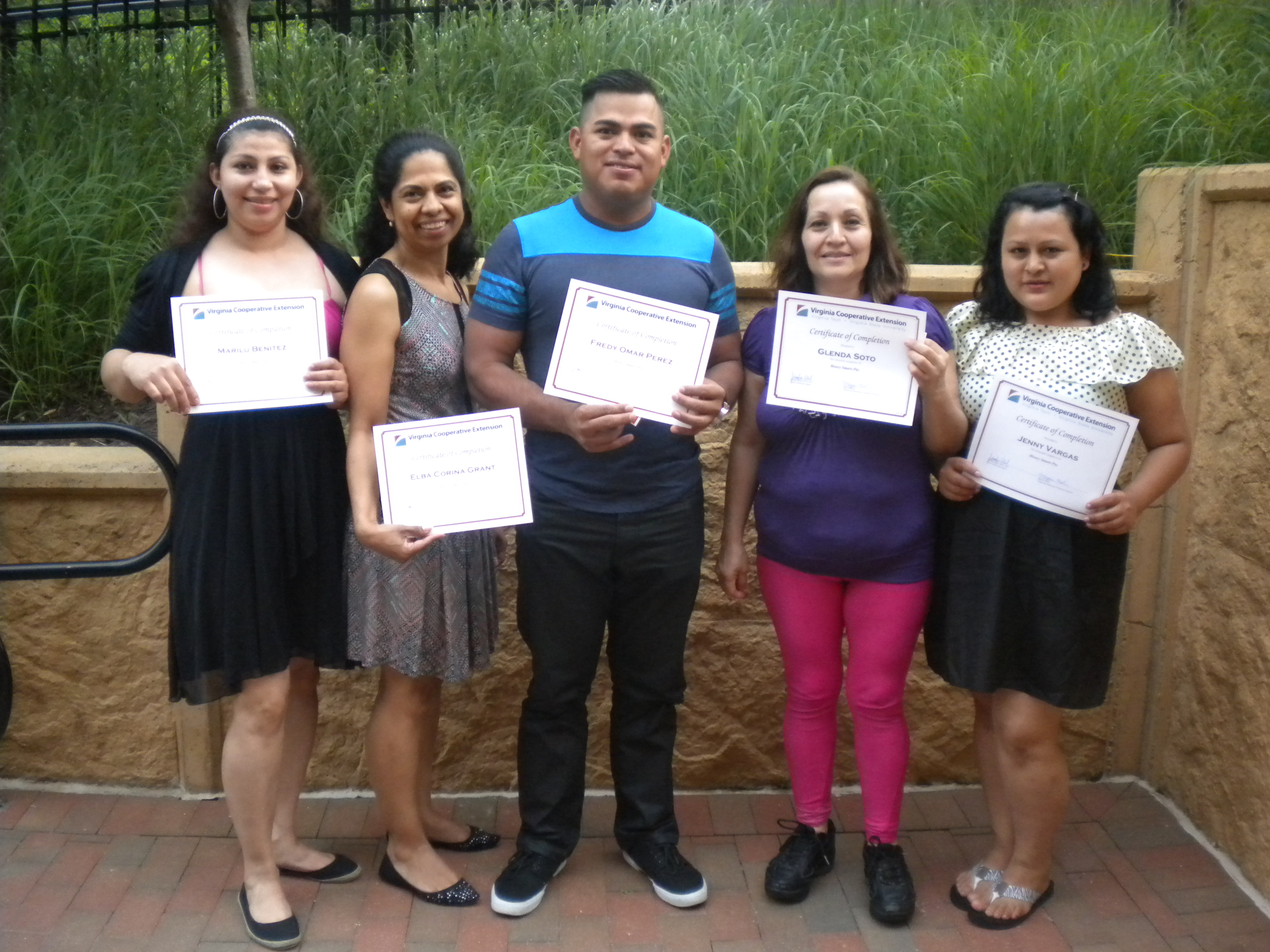 Buchanan Gardens residents Marilu, Corina, Freddy, Glenda, and Jenny display their graduation certificates from the Money Smarts Pay program.